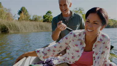 Man and woman laughing in a boat using Stitch the best dating site for 60 and over